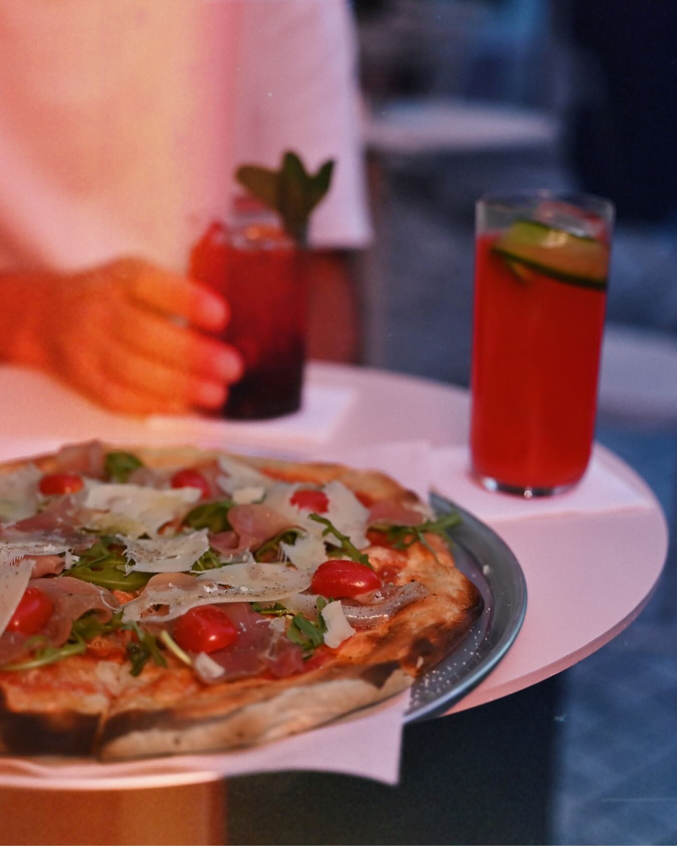 Vibrant red cocktails served alongside a fresh pizza